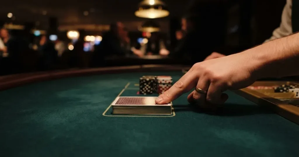 Croupierens händer blandar kort på grönt filt, taklampan speglas i den blanka kortbunten — casinon med bingo i sverige