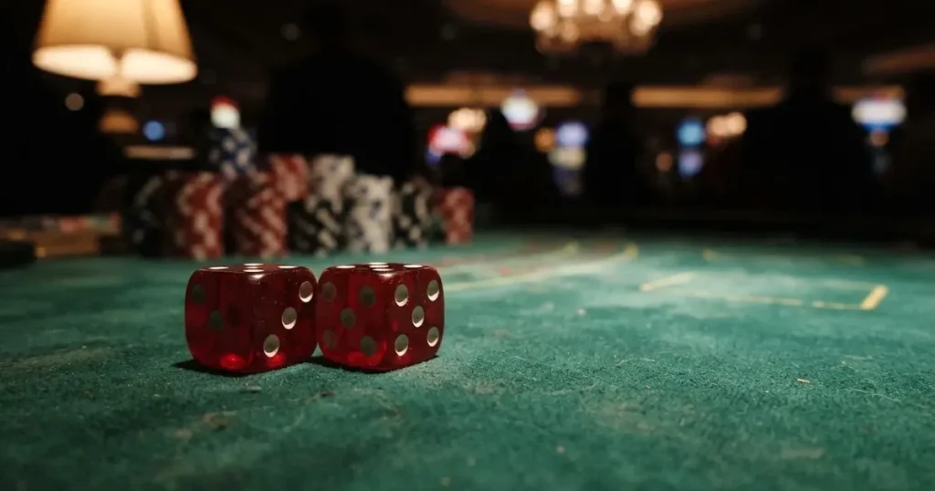 Röda tärningar vilar på grönt filt, bakom dem suddiga torn av spelmarker i kvällsdunklet — svenska online casinon